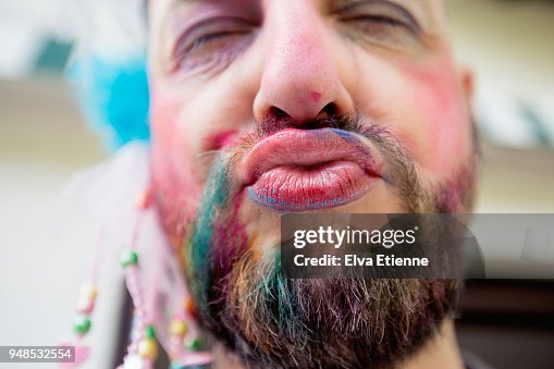 Puckering man wearing lipstick and multicoloured chalk through beard Puckering man wearing lipstick and multicoloured chalk through beard