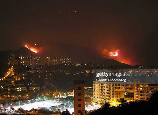 Grass fire is whipped up by high winds on the hillside above Discovery Bay in Hong Kong, China late Friday, November 26, 2004. An aircraft's lights...