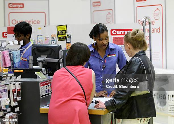 Saleswoman helps two customers at a Currys shop in London, U.K., on Wednesday, May 21, 2008. U.K. Consumer confidence dropped in May to the lowest...