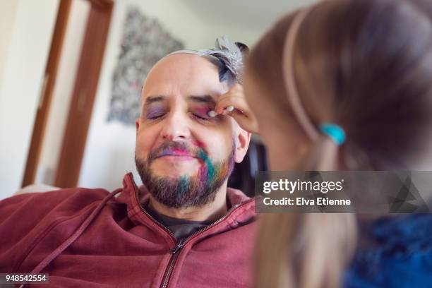 young girl putting makeup on her father - creative makeup stockfoto's en -beelden