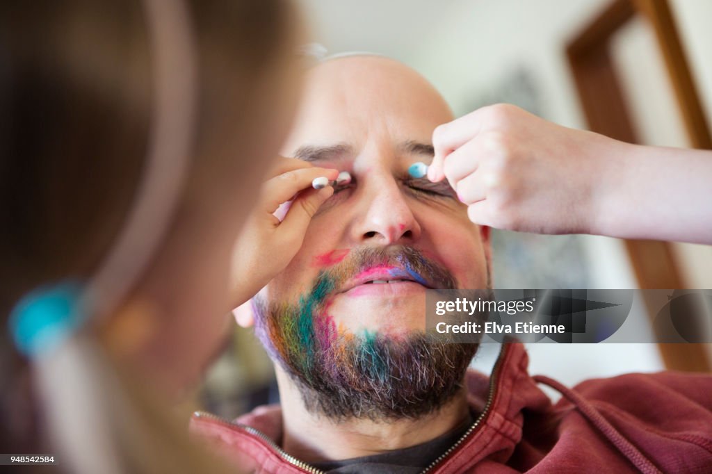 Children applying cosmetics on a man's face and beard