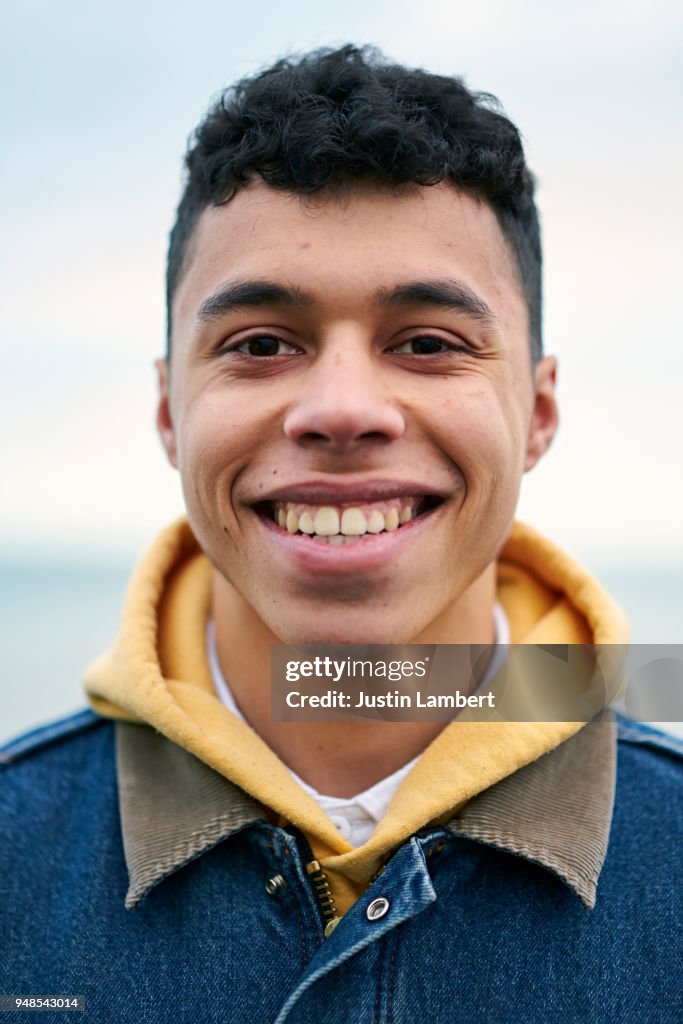 Young mixed race man looking directly to camera smiling in the low cool winter sunlight