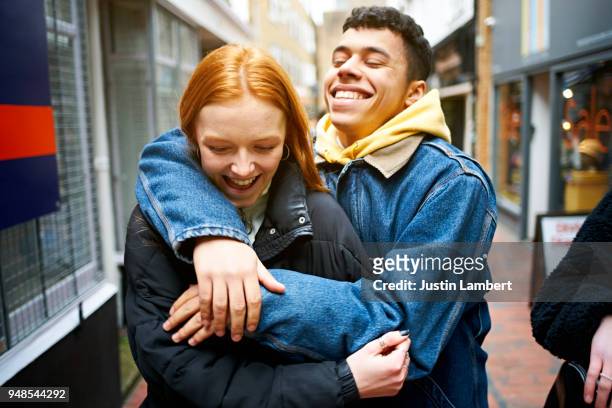 teenage couple having fun hugging and joking while walking together in the street - sussex autumn stock pictures, royalty-free photos & images