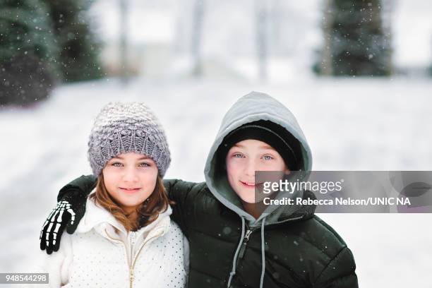 brother and sister with arms around each other outside during a snowfall - hazel bond stock pictures, royalty-free photos & images