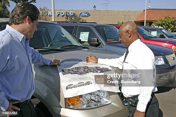 El Cajon Ford sales manager Paul Dyke, left, with salesman Alem Kidane look over a national newspaper ad announcing the "Ford Family Plan" Wednesday...