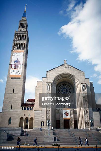 People walk past the Basilica of the National Shrine of the Immaculate Conception on the campus of the Catholic University of America in Washington,...