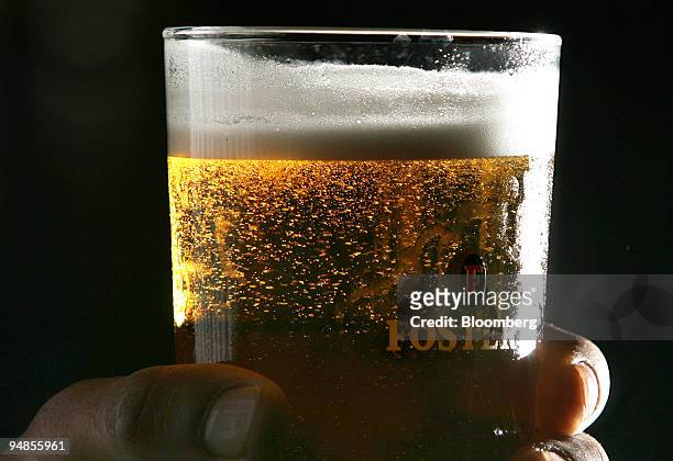 Customer holds a pint of Fosters lager at a public house in Hornchurch, Essex, U.K., on Tuesday, Aug 26, 2008. Heineken NV, the biggest Dutch brewer,...