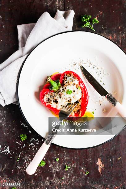 top view of baked in the oven red bell pepper stuffed with minced pork and beef meat, covered with melted cheese, served with fresh parsley in a plate on a wooden table. comfort food. picnic food. - roasted red onion fotografías e imágenes de stock