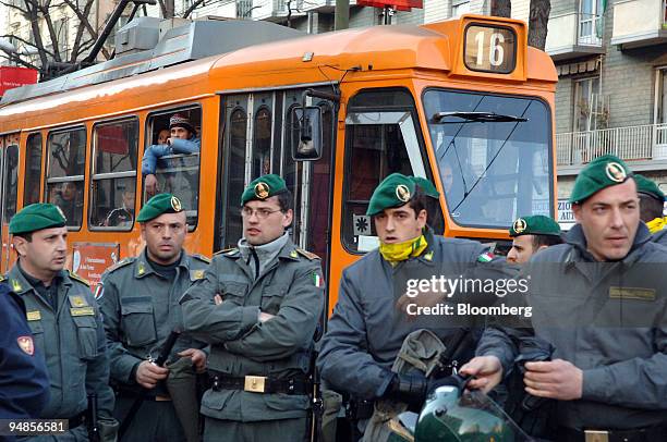 Streetcar waits to let demonstrators pass as riot police from the Guardia di Finanza stand by during a protest prior to the 2006 Winter Olympic...