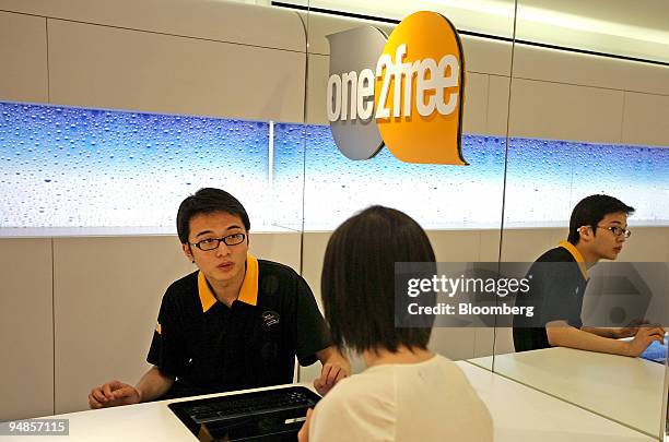 Customer service representatives assist customers inside a One2Free store, owned by CSL New World Mobility Ltd., in Hong Kong, China, on Monday, May...