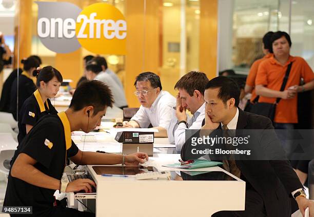 Customer service representatives assist customers inside a One2Free store, owned by CSL New World Mobility Ltd., in Hong Kong, China, on Monday, May...