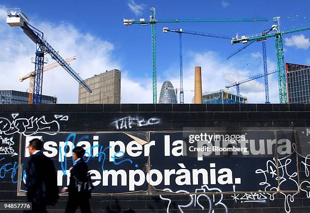 Pedestrians walk past a graffitti covered wall in front of a construction site in Barcelona, Spain, on Tuesday, April 8, 2008. In January, mortgage...
