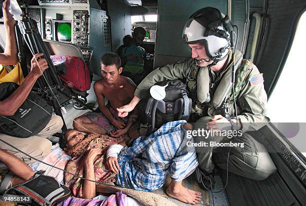 Navy helicopter crewman Chas Dearie, right, of Sulphur, Louisiana, gives the thumbs-up sign to an injured Indonesian villager aboard a navy...