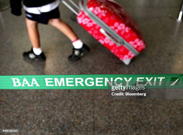 Passenger walks past a BAA emergency exit sign at Gatwick airport in Crawley, Sussex, U.K., on Wednesday, Aug. 20, 2008. Global Infrastructure...