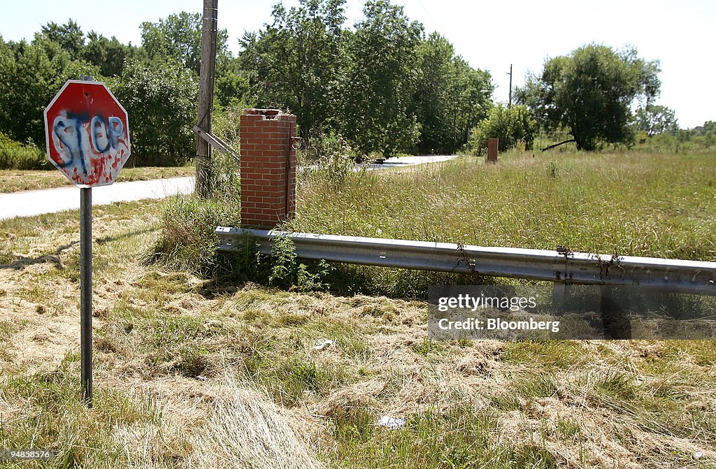 A dilapidated stop sign stands near a vacant field in an are