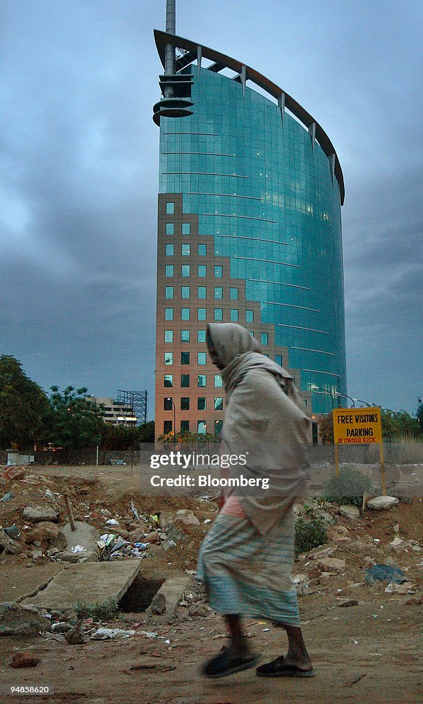 A man walks past the DLF Ltd. Gateway tower in Gurgaon, Indi