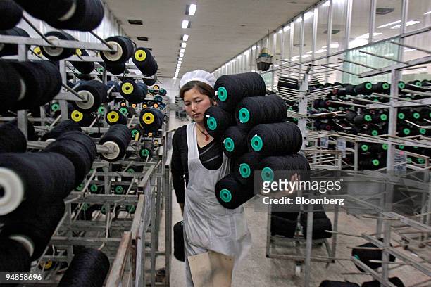Worker transports rolls of yarn to weaving machines at the Jiangsu Sunshine Co. Ltd. Textile factory at Jiangyin, Jiangsu province, China, on...