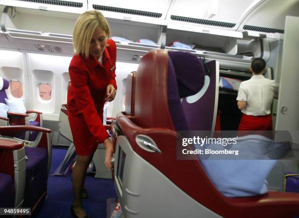 Virgin Atlantic flight attendant, places water in the seat backs of Upper Class seats, onboard an Airbus A340-400, as it is serviced at Logan...
