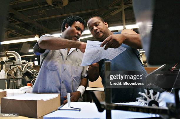 Julio Cuello, left, and Jesus Vargan, look over some paperwork as they work in a National Envelope Corp. Facility in Long Island City, Wednesday,...