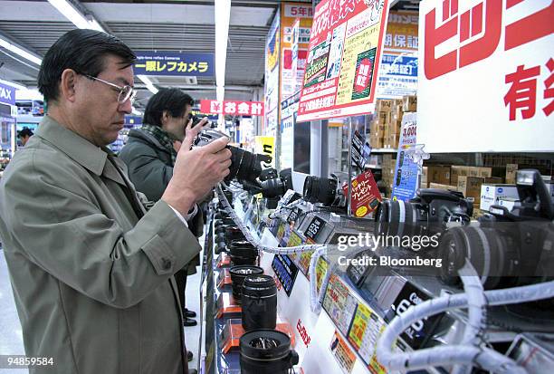 Customers try out Canon digital cameras at an electronics store in downtown Tokyo on Thursday, December 30, 2004. Japan's economy is poised to expand...