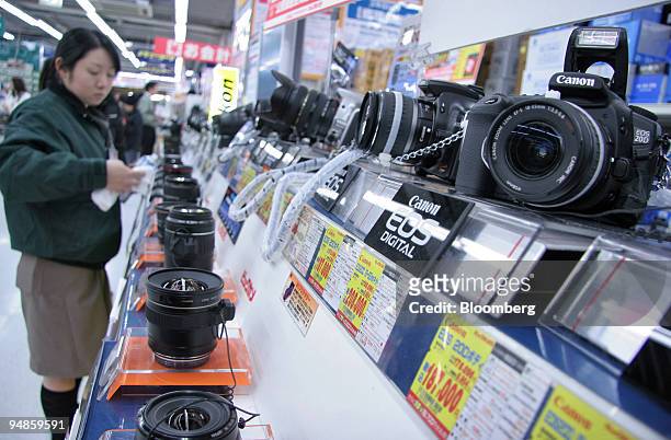 An electronics-shop employee cleans Canon digital cameras and lenses on display in downtown Tokyo on Thursday, December 30, 2004. Japan's economy is...
