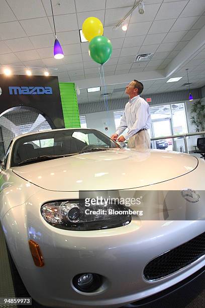 Sales Associate Robert Vermeulen ties balloons to a 2008 MX-5 Miata in the showroom at the Ed Morse Mazda dealership in Port Richey, Florida, U.S.,...