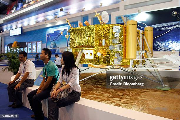 Visitors sit beside a model of the Chinese lunar lander at the 7th China International Aviation & Aerospace Exhibition in Zhuhai, China, on Monday,...