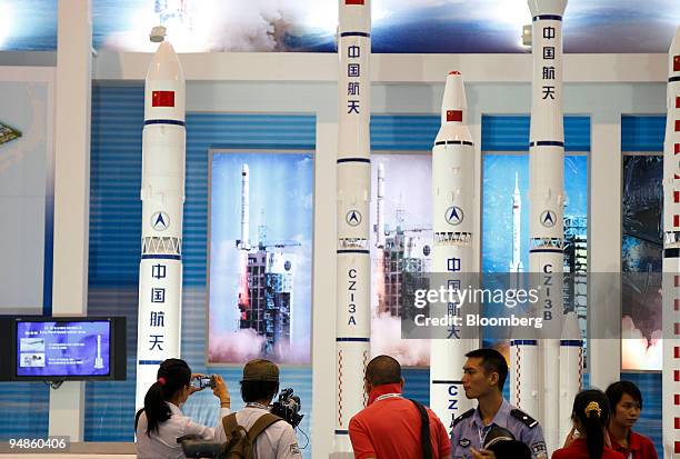 Visitors stand in front of models of Changzheng "Long March" rockets at the 7th China International Aviation & Aerospace Exhibition in Zhuhai, China,...