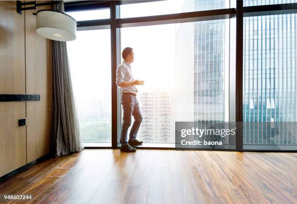 geschäftsmann steht am fenster und trinkt kaffee - coffee top view stock-fotos und bilder