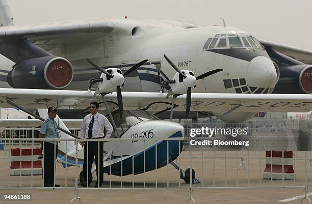 Chinese exhibitors and their locally-made BD-205 amphibious aircraft are dwarfed by an Ilyushin IL-76 transport plane Monday, November 1, 2004 at the...