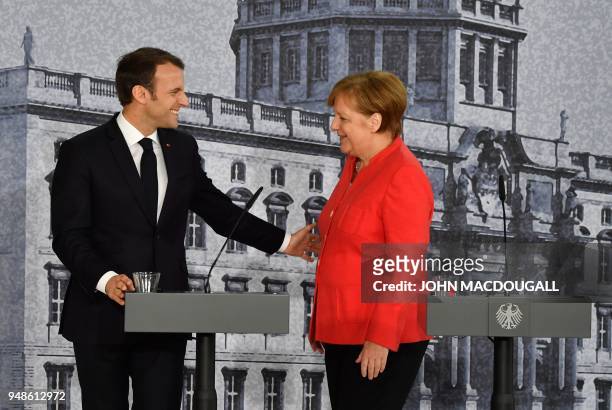 German Chancellor Angela Merkel and French President Emmanuel Macron greet eachother warmly at the end of a joint press conference on April 19, 2018...
