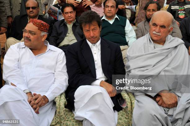 Imran Khan, head of the Tehrik-e-Insaaf party, center, waits to talk to supporters at an All Parties Democratic Movement rally in Lahore, Pakistan,...