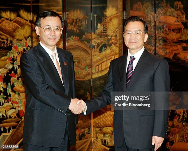 Chinese Premier Wen Jiabao, right, shakes hands with Japanese Finance Minister Sadakazu Tanigaki at a meeting of European and Asian finance ministers...