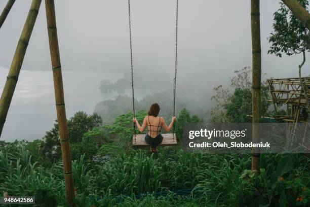 frau auf der schaukel über den dschungel und den see in bali - idyllic lake stock-fotos und bilder