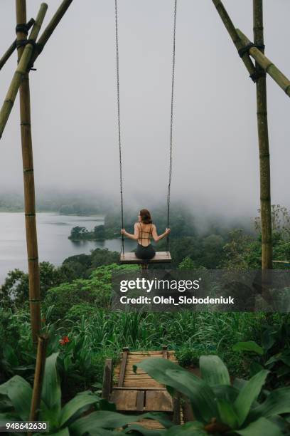 woman on the swing over the jungles and lake  in bali - bali stock pictures, royalty-free photos & images