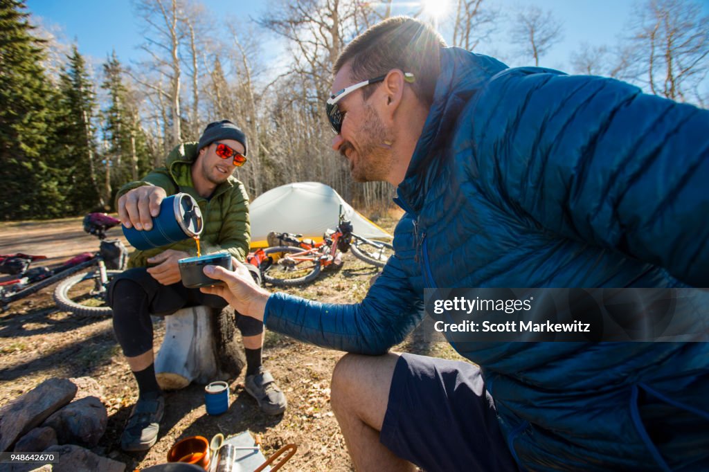 Two men having morning coffee at their campsite