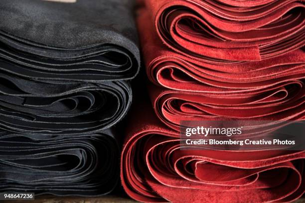 rolls of processed leather sits stacked at a tannery - leather industry stock pictures, royalty-free photos & images