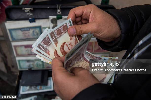 a currency trader counts iranian rial banknotes at a money exchange market - iran stock pictures, royalty-free photos & images