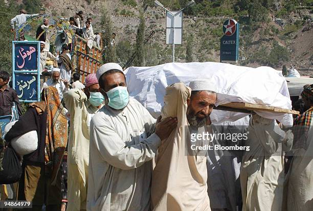 Volunteers carry injured people for treatment in Balakot, northern Pakistan on Wednesday, October 12, 2005. Pakistan's government will immediately...