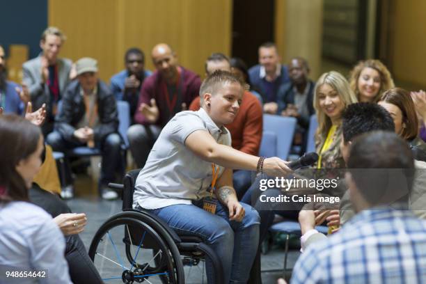 female speaker in wheelchair giving microphone to audience - standing out from the crowd (expressão inglesa) imagens e fotografias de stock