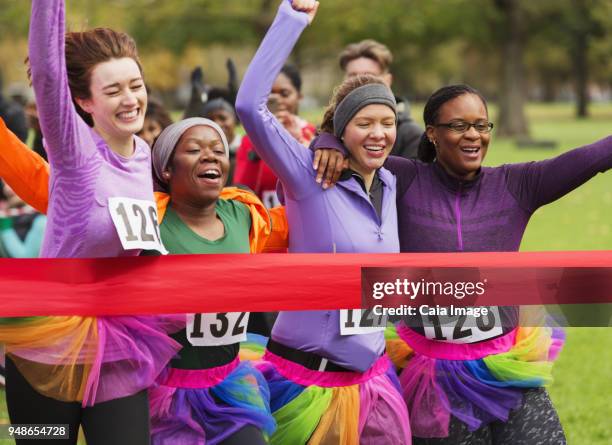 women friend runners in tutus running, crossing charity run finish line - person with arms crossed stock pictures, royalty-free photos & images