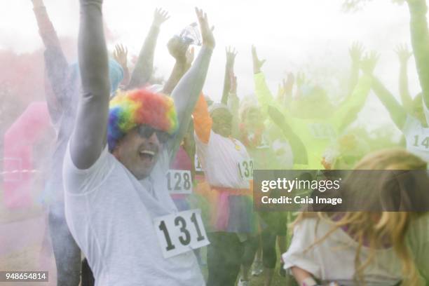 playful charity run runners throwing holi powder - paint race stock pictures, royalty-free photos & images