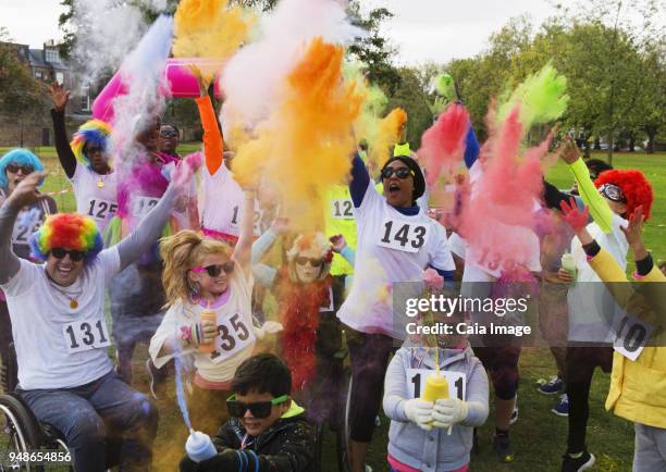 playful charity run runners celebrating with holi powder in park - holirun stock-fotos und bilder