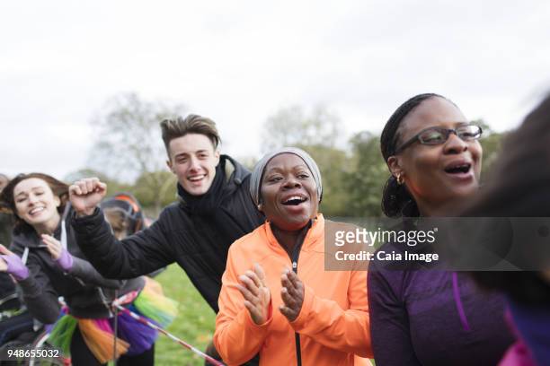 enthusiastic spectators cheering at charity run in park - race spectator stock pictures, royalty-free photos & images