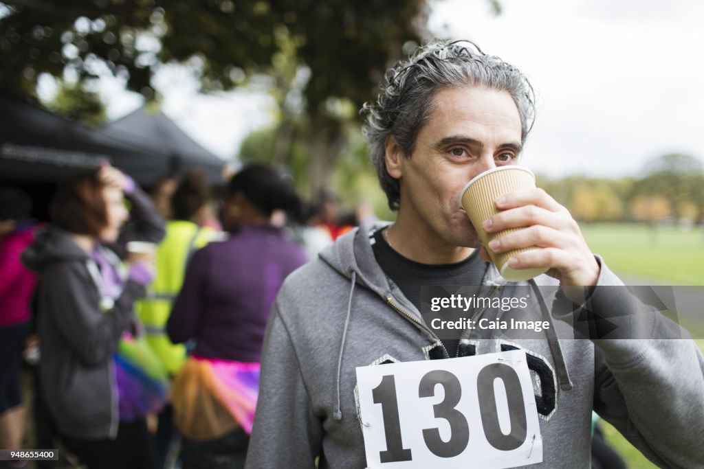 Male marathon runner drinking water in park