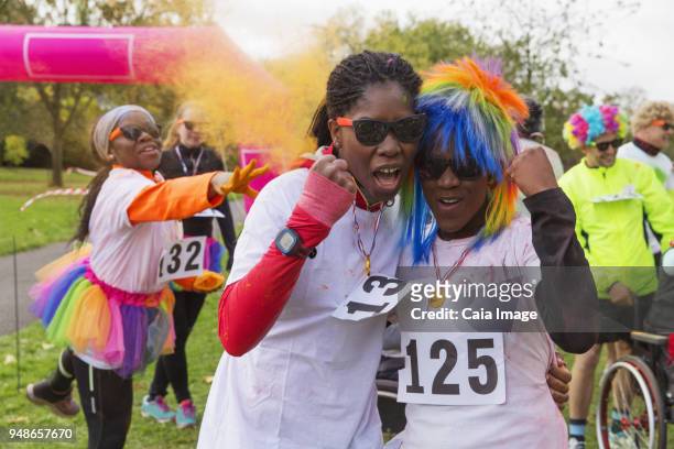 portrait confident, enthusiastic female runners cheering at charity run in park - running fancy dress stock-fotos und bilder