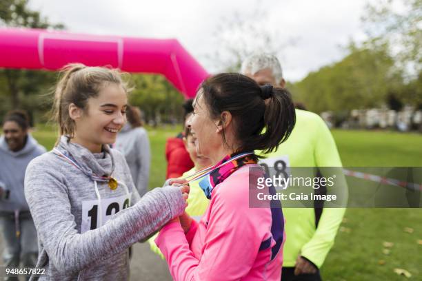 Daughter placing medal around neck of mother at charity run in park