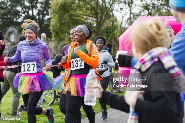 female runners in tutus running at charity race in park - charity benefit stock pictures, royalty-free photos & images