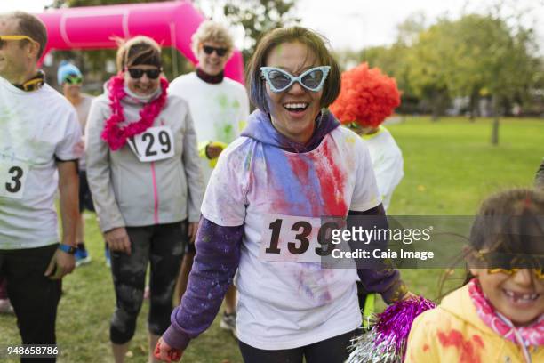 portrait smiling, playful female runner in silly sunglasses at charity run in park - paint race stock pictures, royalty-free photos & images