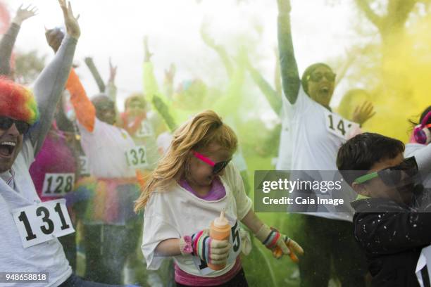 playful crowd of runners throwing holi powder at charity run - color run stock-fotos und bilder